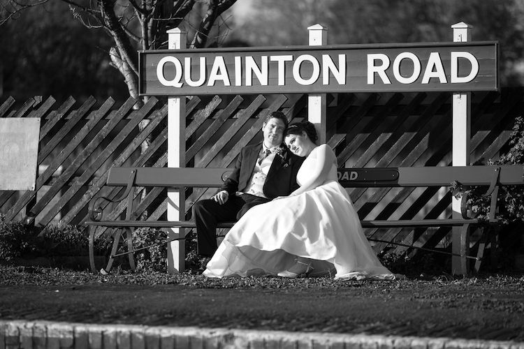 Emma and James sit in front of the historic Quainton Road railway station sign