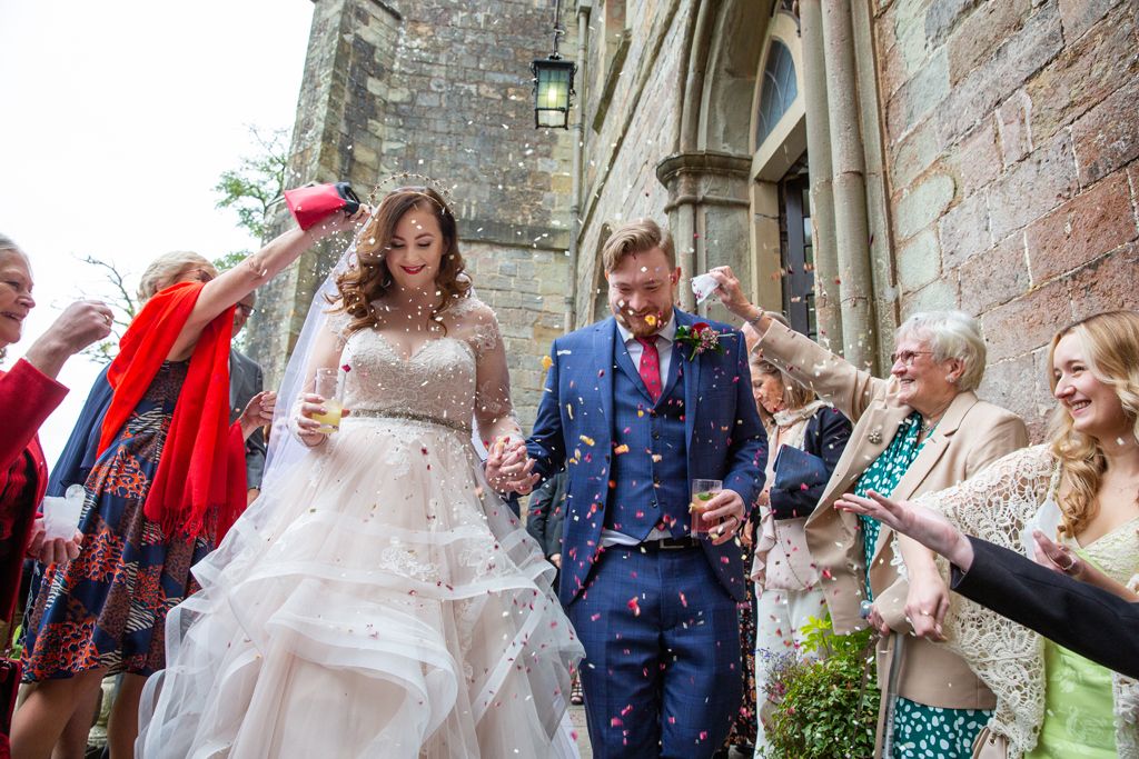Aimee and Simon's guests throwing confetti as the couple walk down the steps of Clearwell Castle. Photo thanks to Mark Lord Photography.