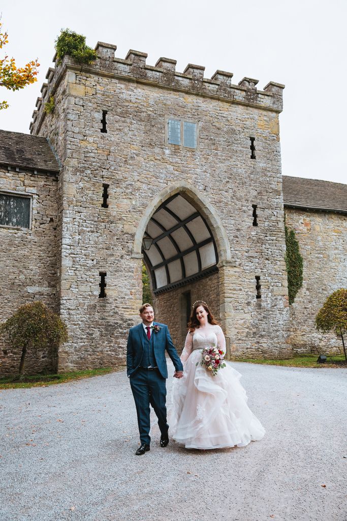 Aimee and Simon walking hand in hand out of the arch entrance to Clearwell Castle. Photo thanks to Mark Lord Photography.