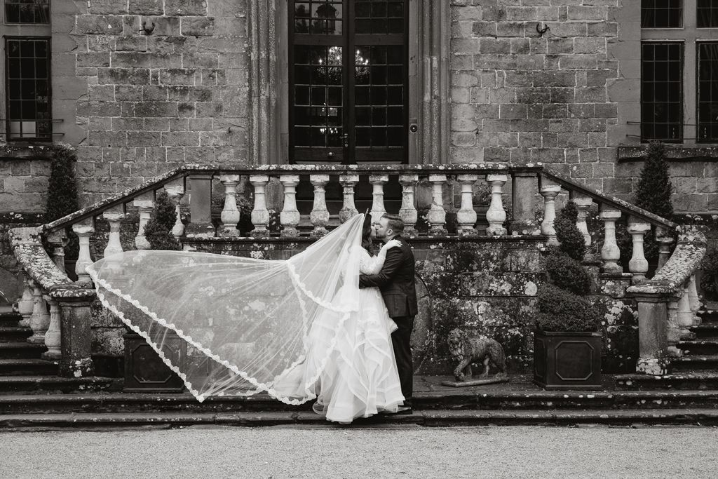 Aimee and Simon wedding photo outside Clearwell Castle - Aimee's veil blowing in the wind. Photo thanks to Mark Lord Photography.