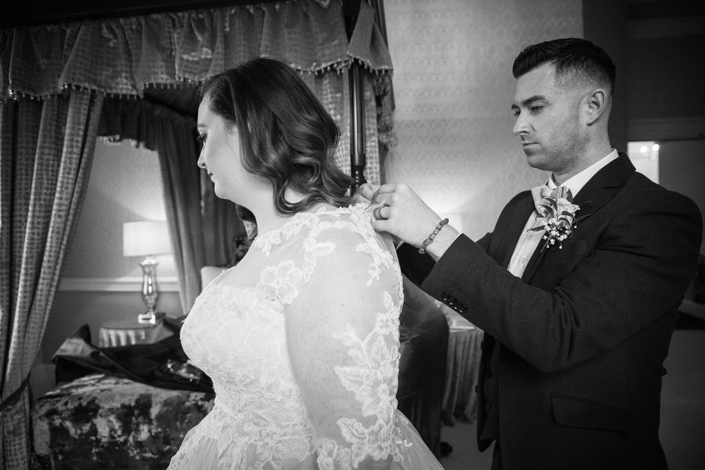 Aimee having her dress buttons done up by her bridesman on the morning of her wedding. Photo thanks to Mark Lord Photography.