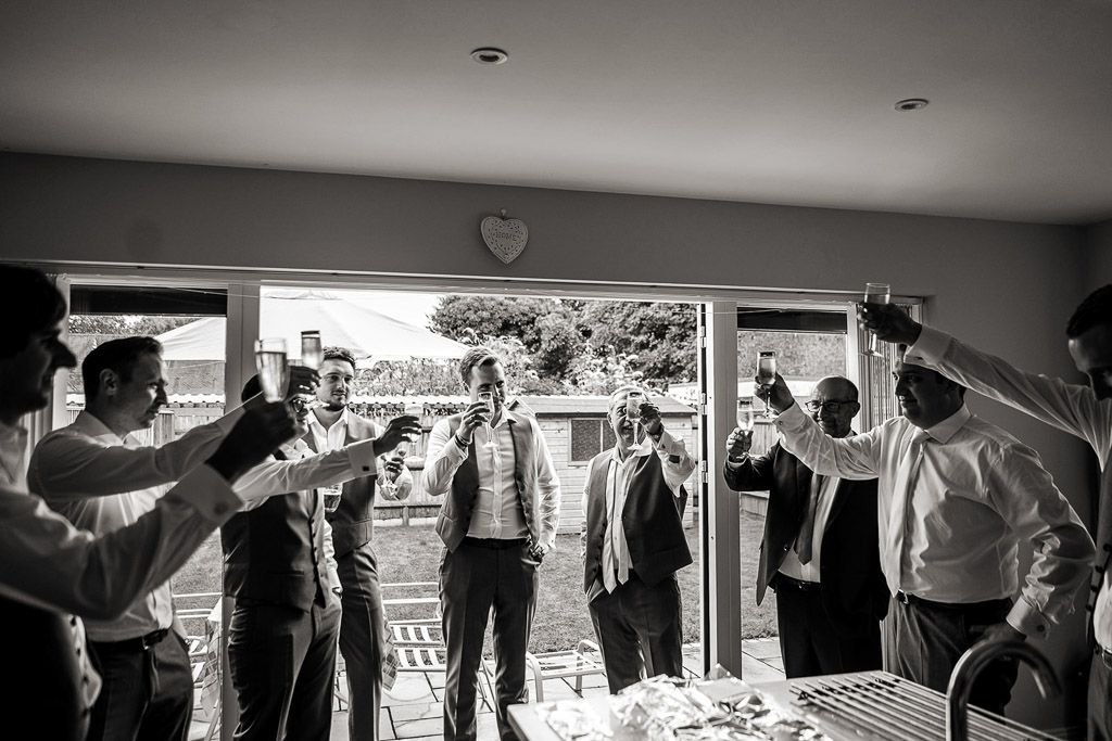 Toast to the groom whilst he gets ready at home. Cheers with champagne! Wedding photo by Allister Freeman. Videography by Veiled Productions - unique wedding videographer Bury Court Barn