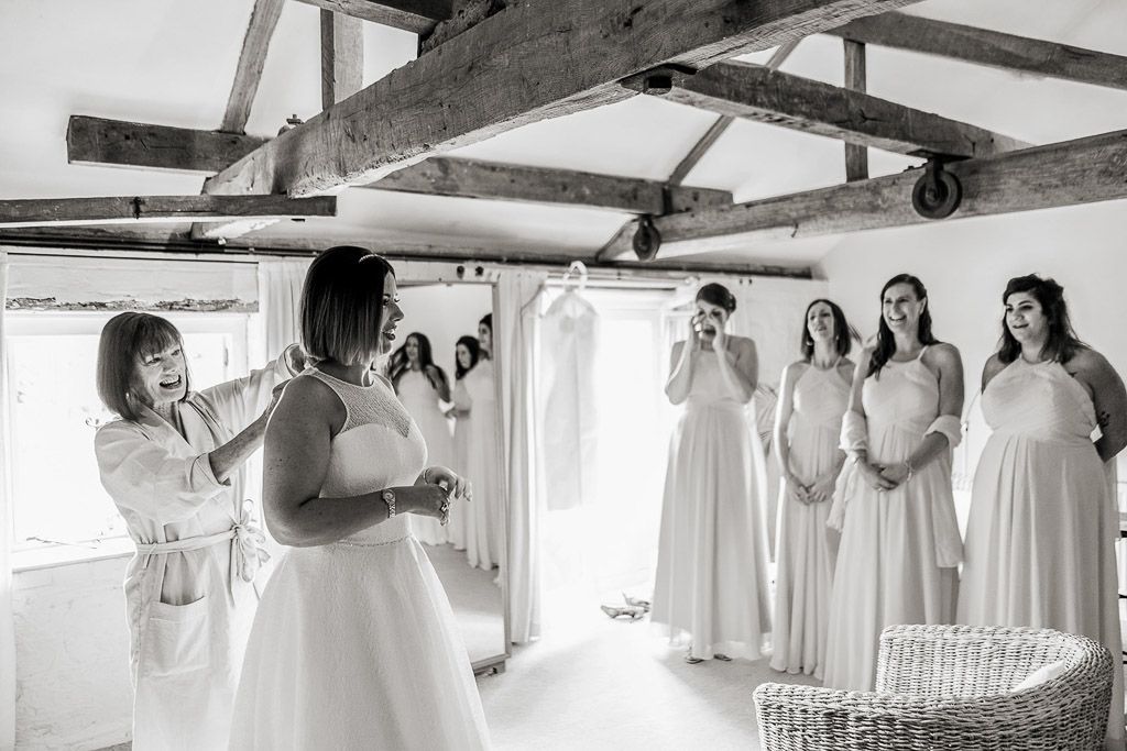 First time Amy shows her wedding dress to her bridesmaids. Wedding photo by Allister Freeman. Videography by Veiled Productions - unique wedding videographer Bury Court Barn