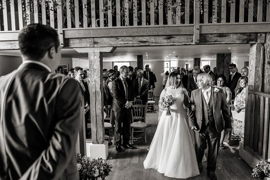 Amy walking down the aisle with her Dad to greet Mario ready for their wedding ceremony. Wedding photo by Allister Freeman. Videography by Veiled Productions - unique wedding videographer Bury Court Barn