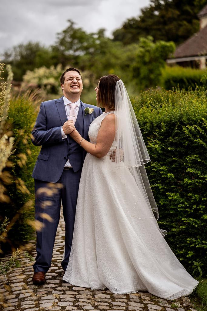 Amy and Mario laughing together as a newly married couple. Wedding photo by Allister Freeman. Videography by Veiled Productions - unique wedding videographer Bury Court Barn