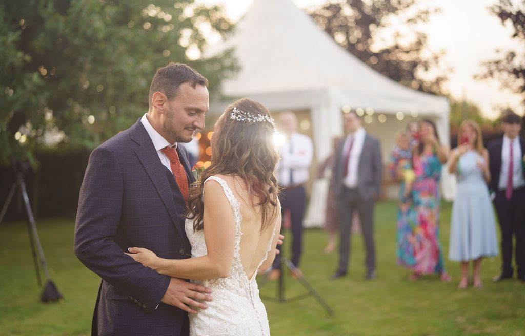 Bex and Dan dancing their first dance in front of their guests outside in the gardens of Redhouse Barn. Photo thanks to J Bidmead Photography.