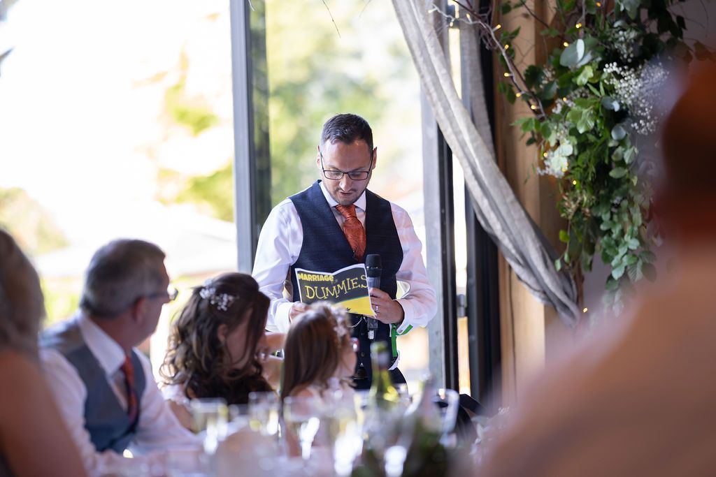 Dan - the groom - giving his speech with 'wedding speech for dummies' fake book to reference from