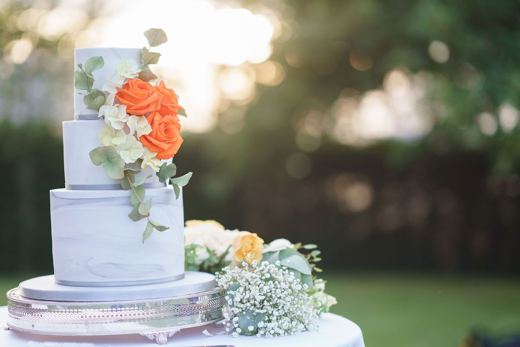 Bex and Dan wedding cake outside of Redhouse Barn ready to be cut as the sunset across the gardens. Designed and made by Ben the Cake Man. Photo thanks to J Bidmead Photography.