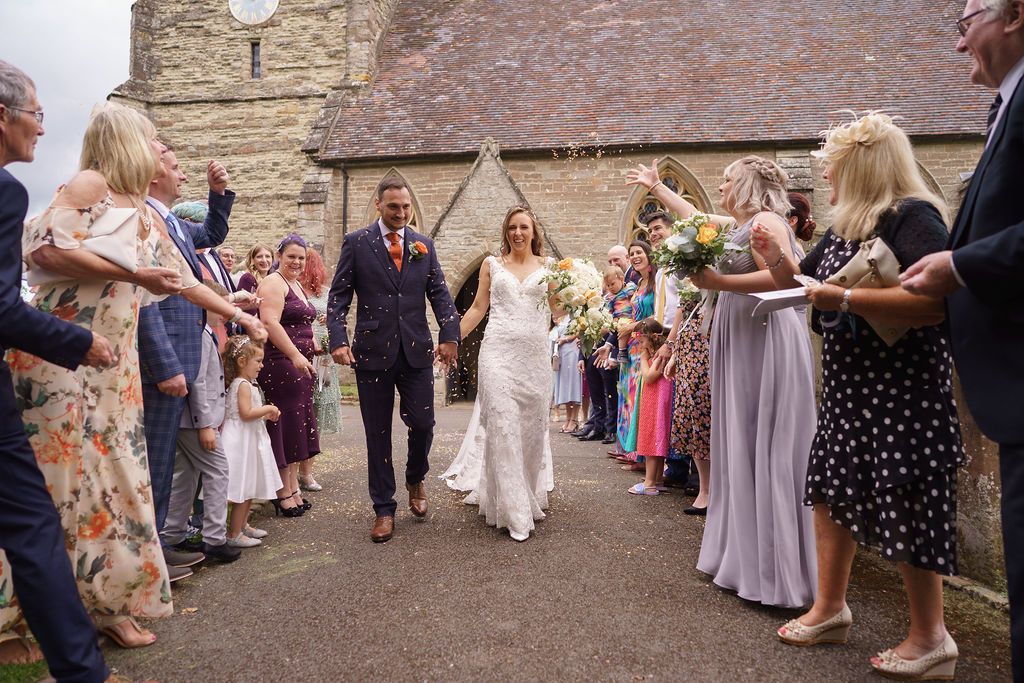 Bex and Dan leave the church as newlyweds whilst all their guests throw the confetti - photo thanks to J Bidmead Photography