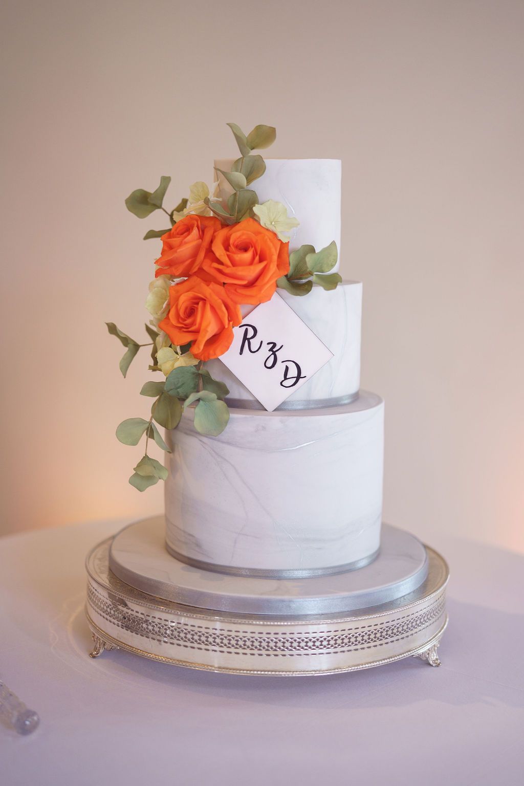 Bex and Dan white wedding cake with silver ribbon and orange fresh flowers with eucalyptus at Redhouse Barn