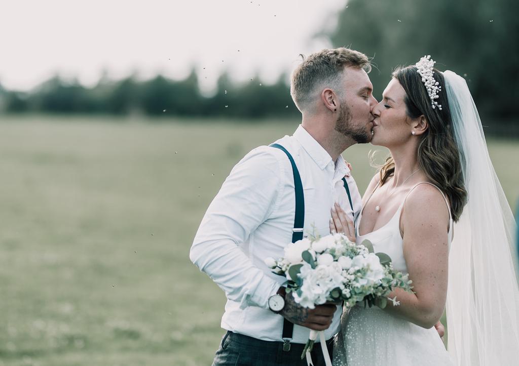 Erin and Vinnie kiss in the fields behind The Tythe Barn - photography by The Kensington Photographer