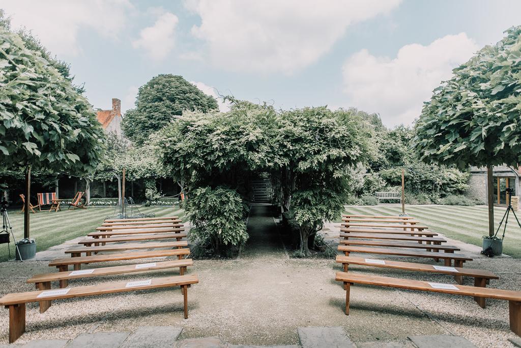 The outside area for a ceremony at The Tythe Barn with benches in the courtyard - photo by The Kensington Photographer
