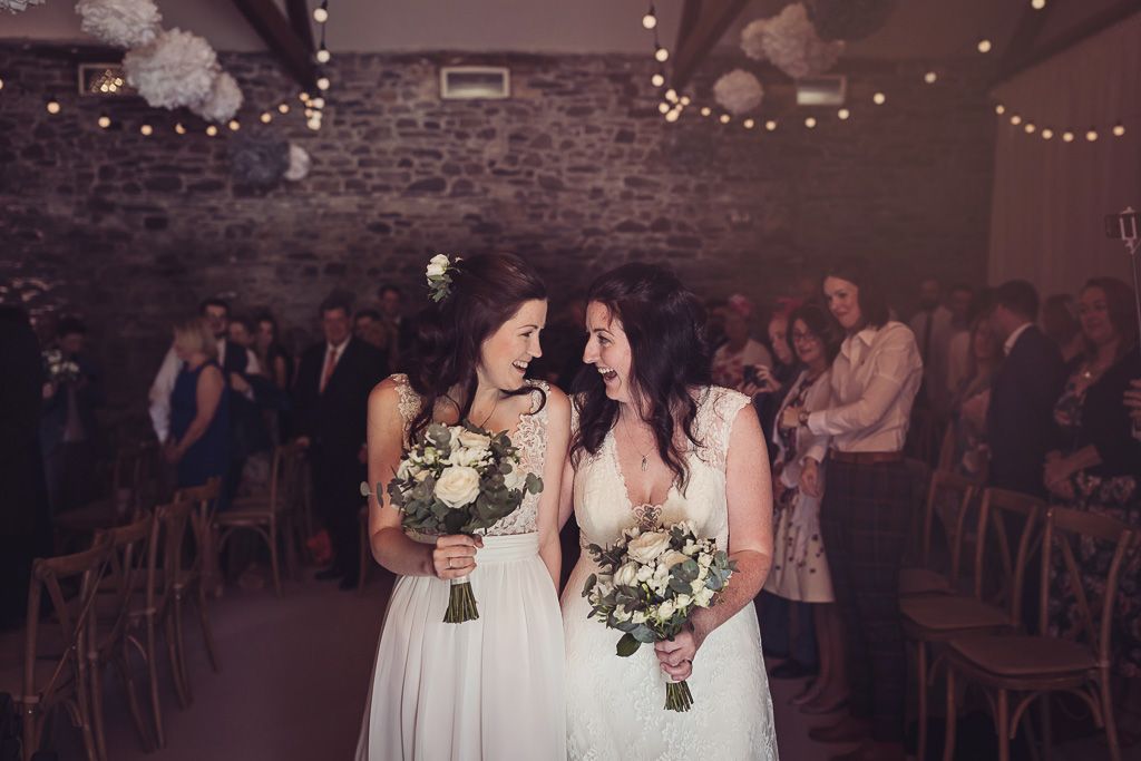 Kay and Rach leaving their ceremony as newlyweds. Sophisticated Barn Wedding. Photography by Tiree Dawson Photography. Videography by Veiled Productions. Flowers by Floral Boutique Cockermouth. Sophisticated New House Farm wedding in the Summer 2019.