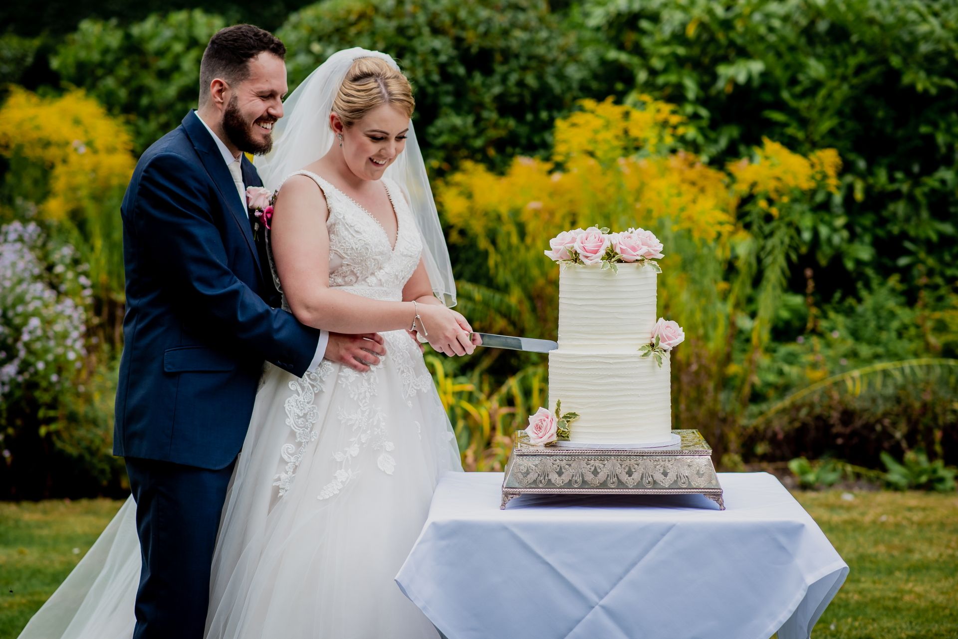 Leah and Nic cutting their gorgeous two tier wedding cake with pink flowers by Daisy Cakes. Photo thanks to Damien Vickers Photography. 