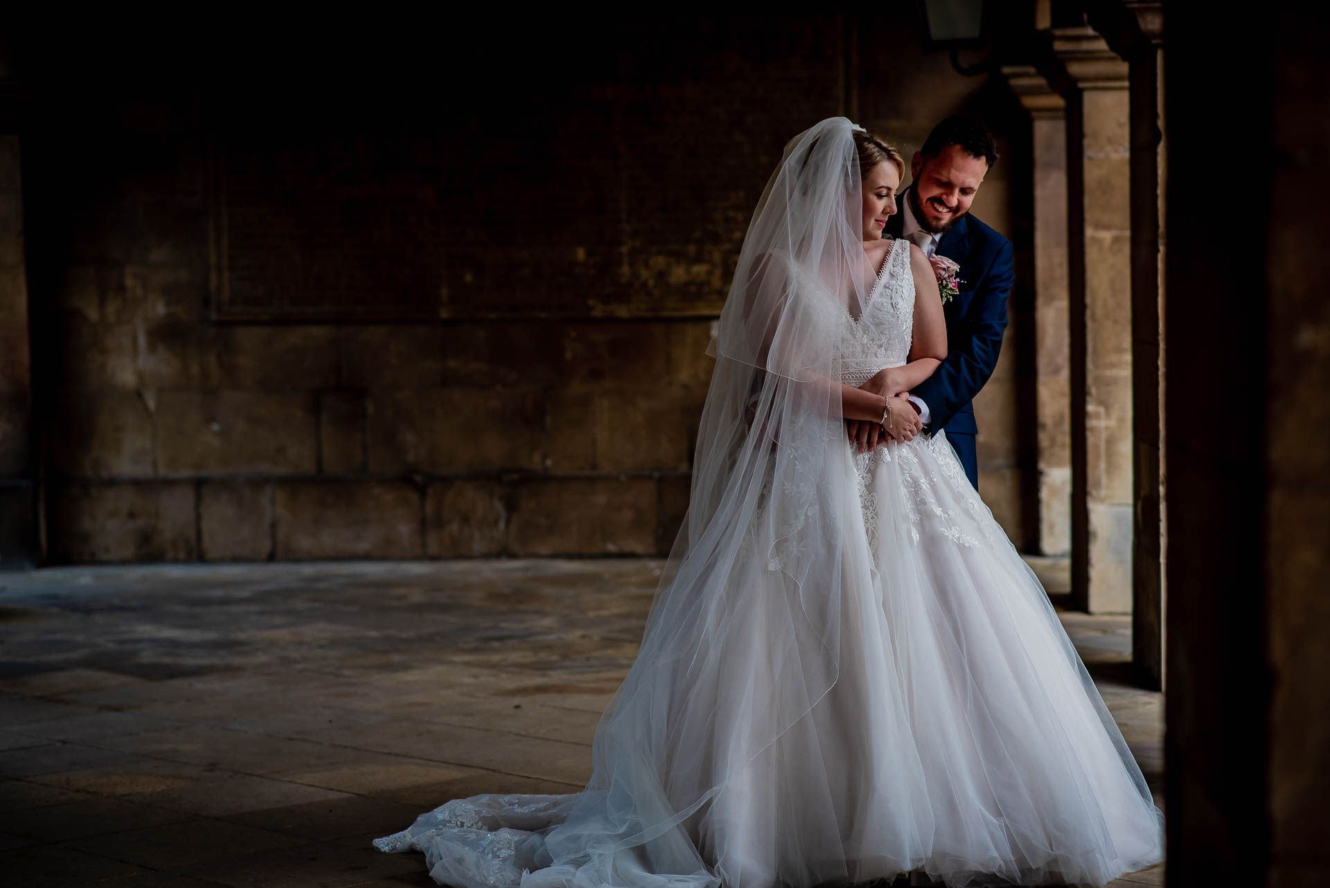 Leah and Nic in the courtyard of Emmanuel College, Cambridge University. Arms around each other and smiling. Photo by Damien Vickers Photography. 