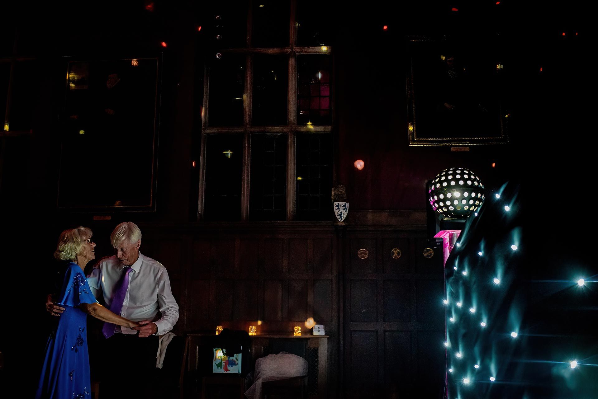 Two wedding guests dancing on the dancefloor with the disco lights in the right of the image. Photo by Damien Vickers Photography. 