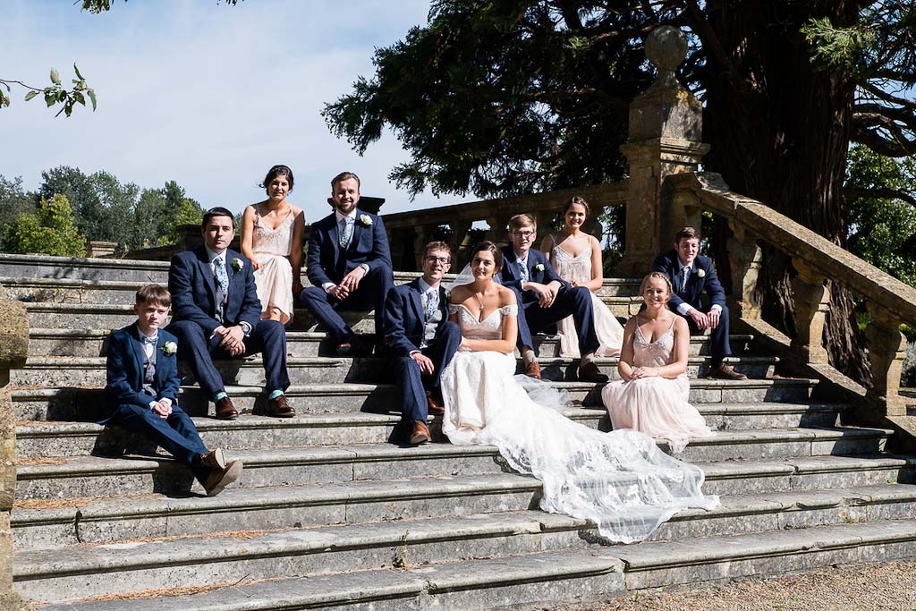 Rebecca and Mark wedding party - bridesmaids and groomsmen on the steps at Eynsham Hall - photography by Rob Wheal Photography | Oxfordshire wedding videography by Veiled Productions