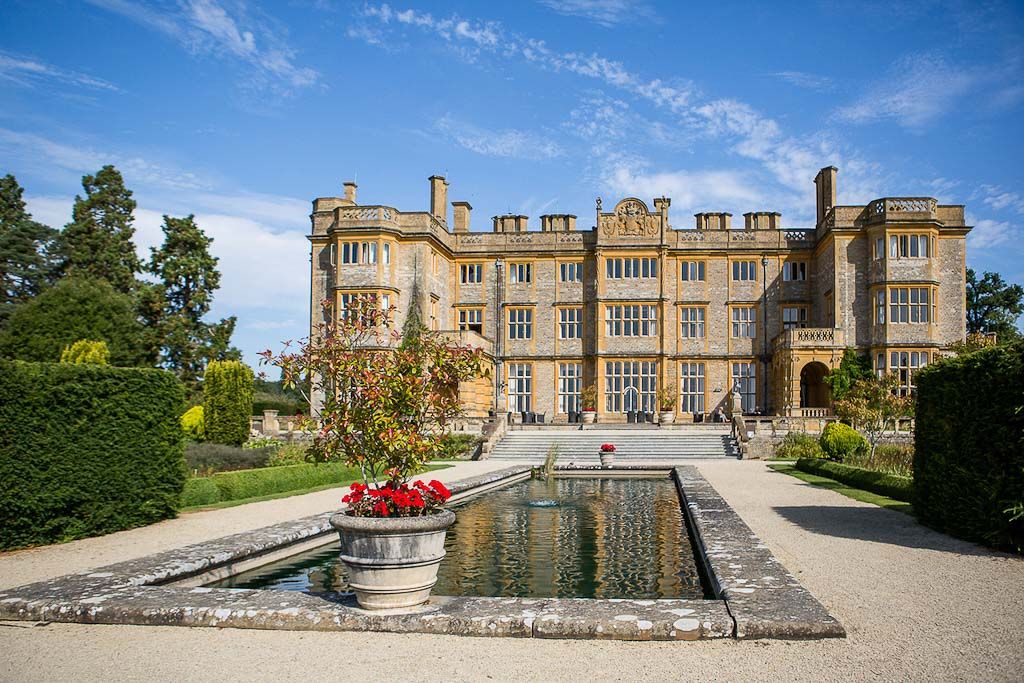 View of Eynsham Hall from the landscaped gardens with the pond in the centre - photography by Rob Wheal Photography | Oxfordshire wedding videography by Veiled Productions