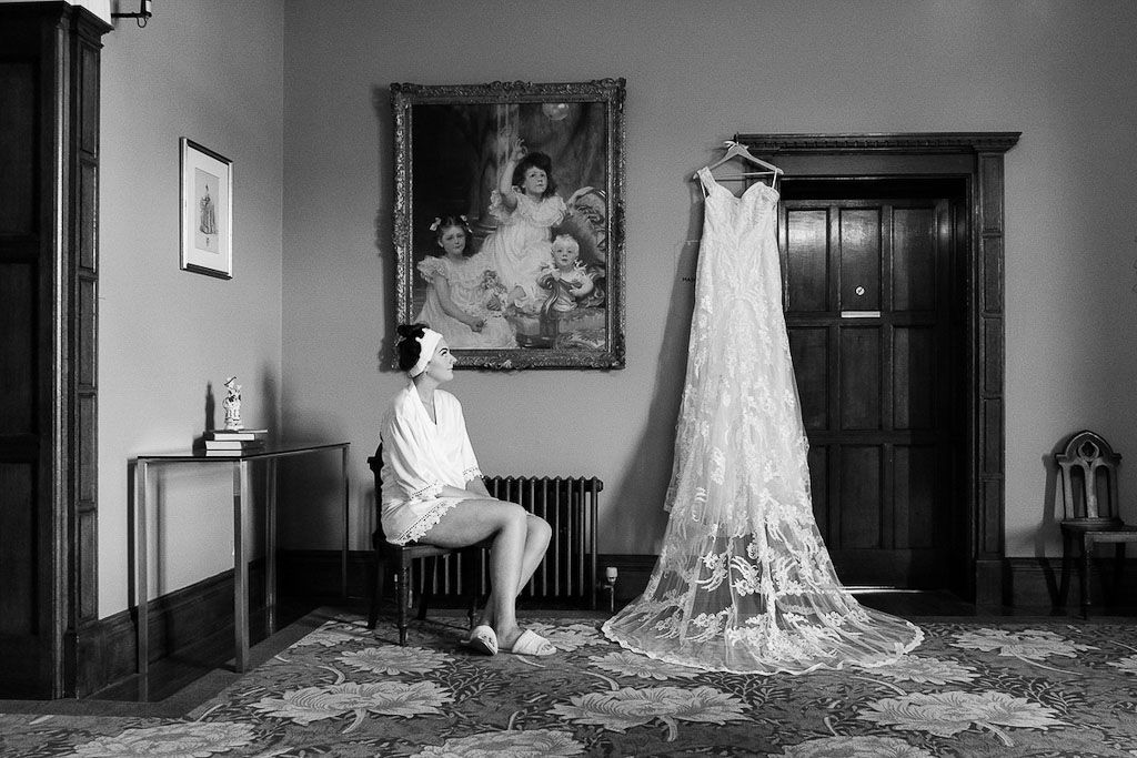 Rebecca getting ready for her wedding ceremony looking up at her wedding dress - photography by Rob Wheal Photography | Oxfordshire Wedding Videography by Veiled Productions