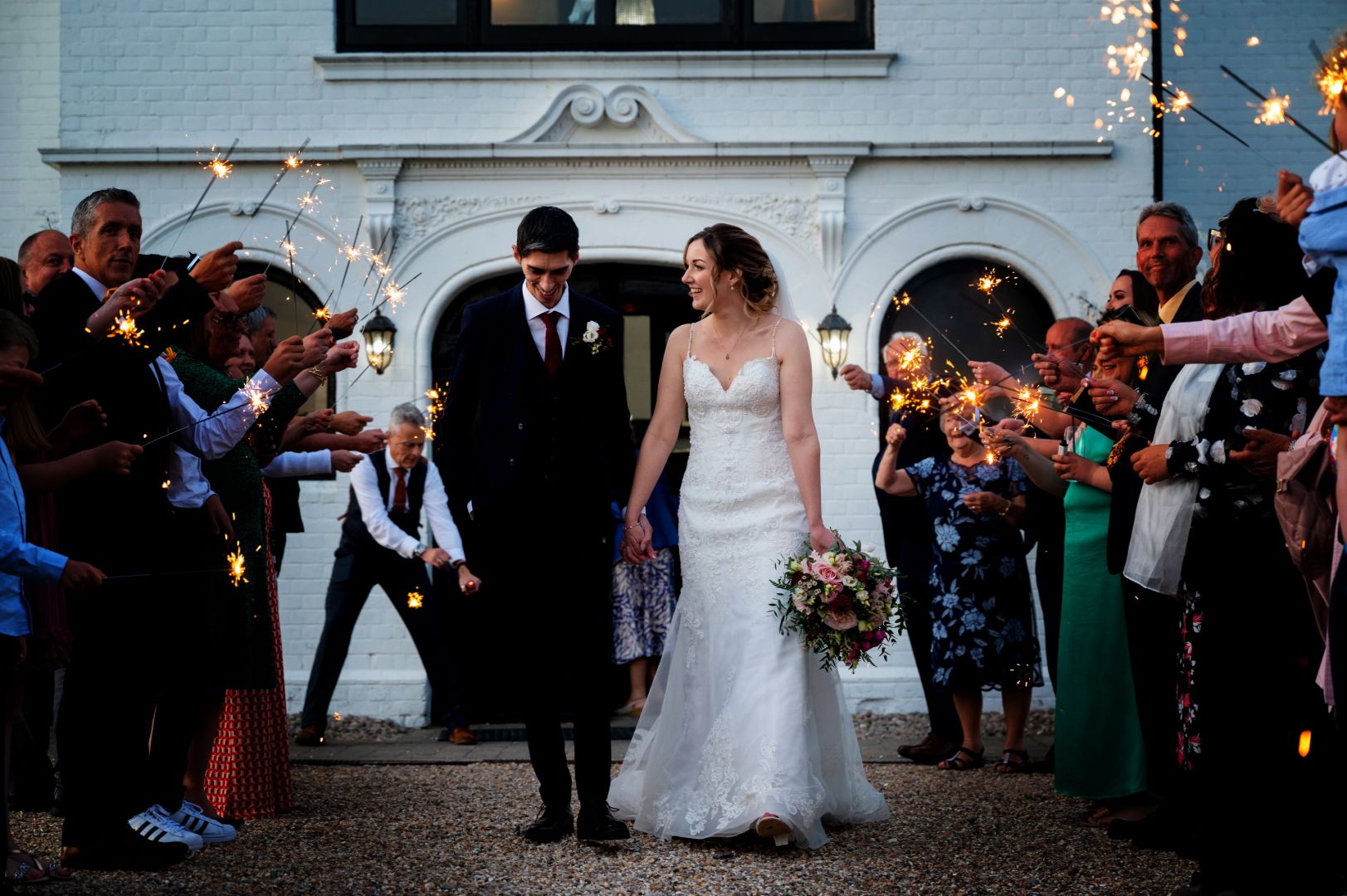 Ross and Sophie walk down an aisle of sparklers held by their guests outside the front of Swynford Manor. Photo thanks to Foutain Photography. 