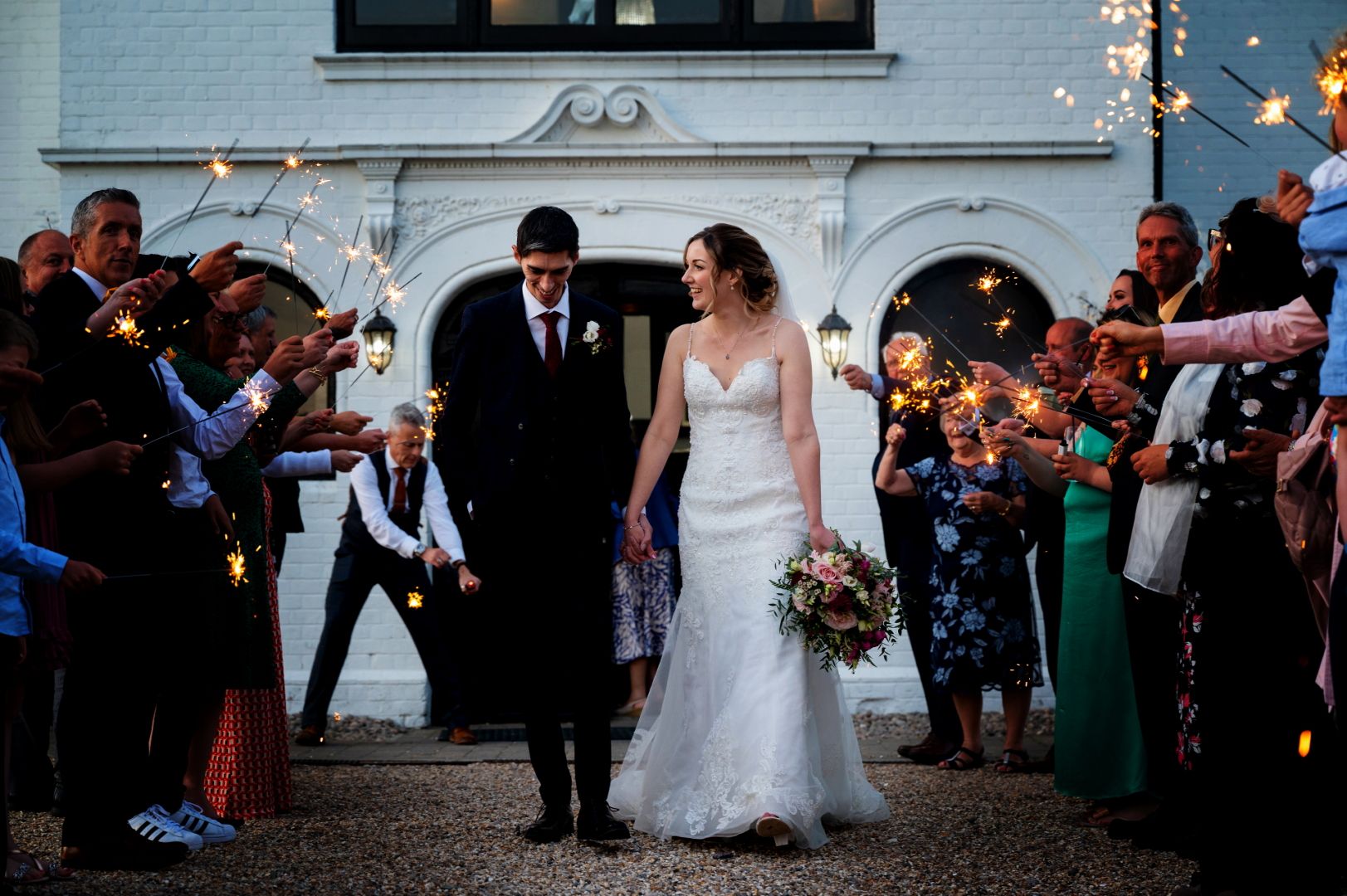 Ross and Sophie walk down an aisle of sparklers held by their guests outside the front of Swynford Manor. Photo thanks to Foutain Photography.