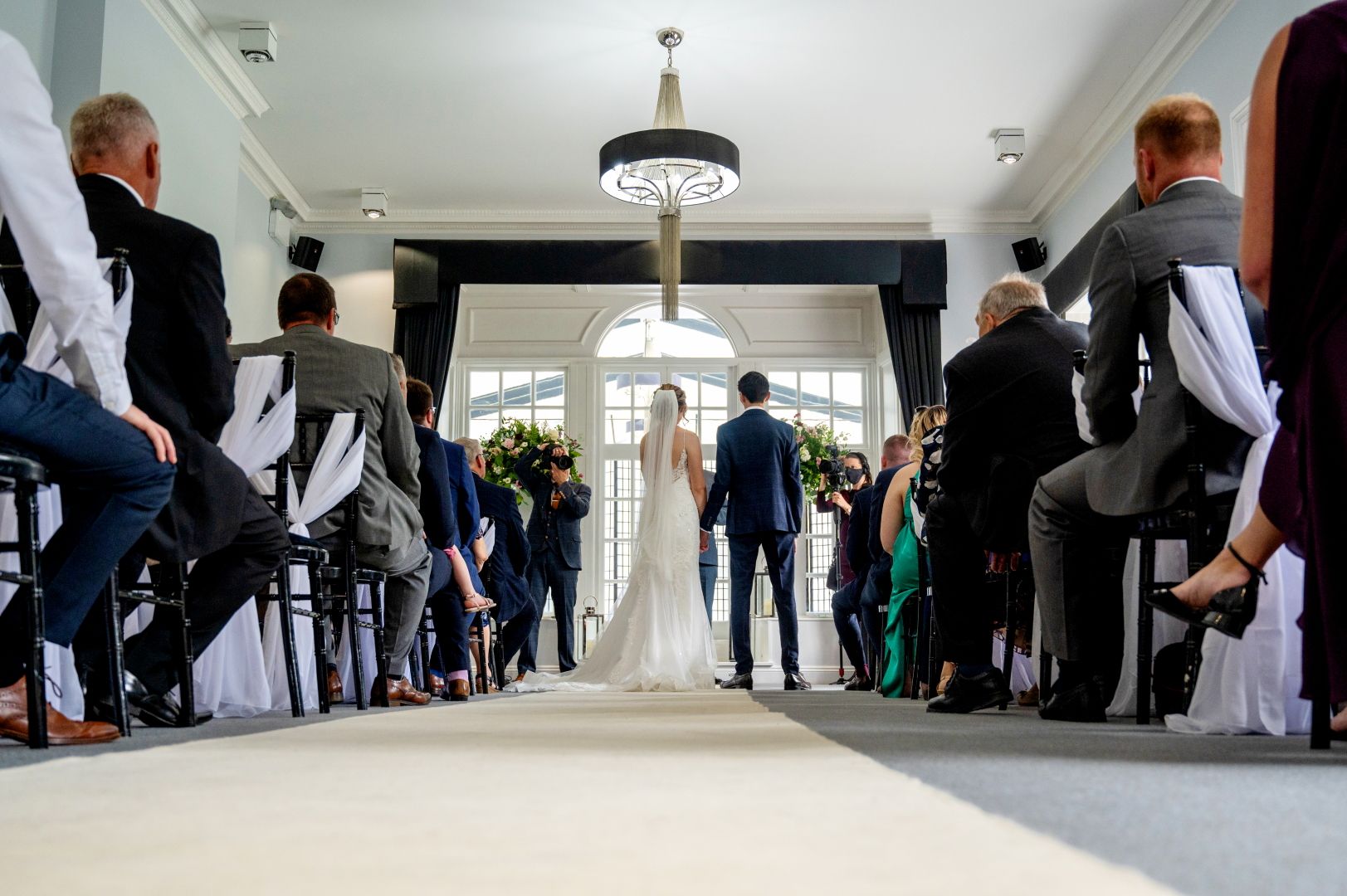 A low angled shot with Sophie and Ross at the bottom of the aisle about to make their wedding vows during their civil ceremony at Swynford Manor. Photo by Fountain Photography.