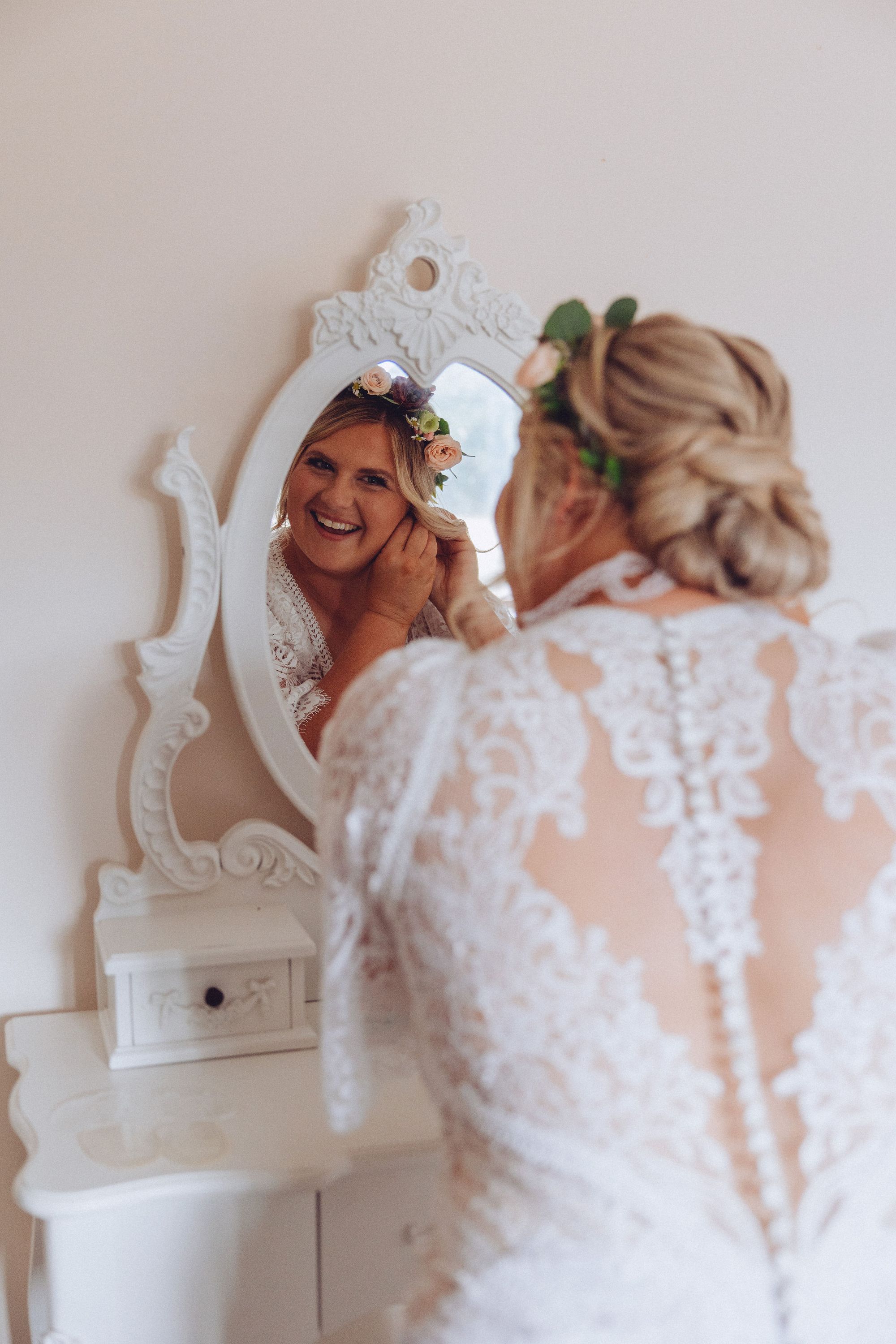 Nor looking into the mirror putting in her wedding day earrings wearing her lace wedding dress. Photo thanks to Fordtography.