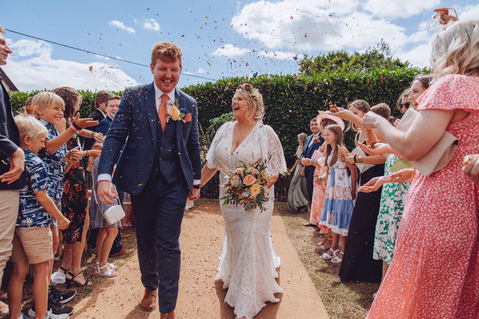 Confetti exit from their wedding ceremony back down the aisle in the farm gardens. Nor and Dan and their guests can't stop laughing. Photo thanks to Fordtography.