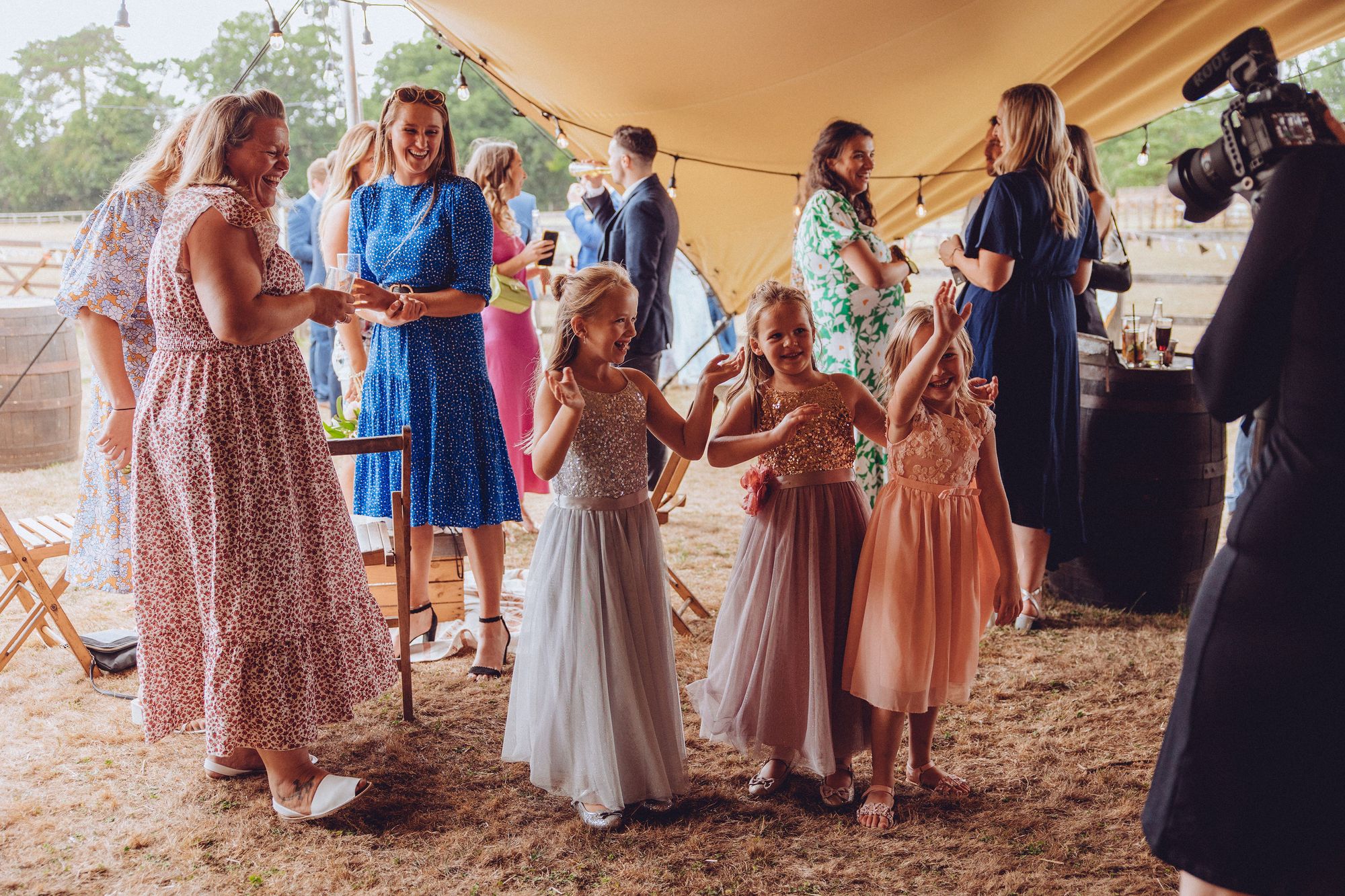 Rachel from Veiled Productions filming the children at Nor and Dan's wedding waving at the camera. Parents are laughing in the background. Photo thanks to Fordtography.