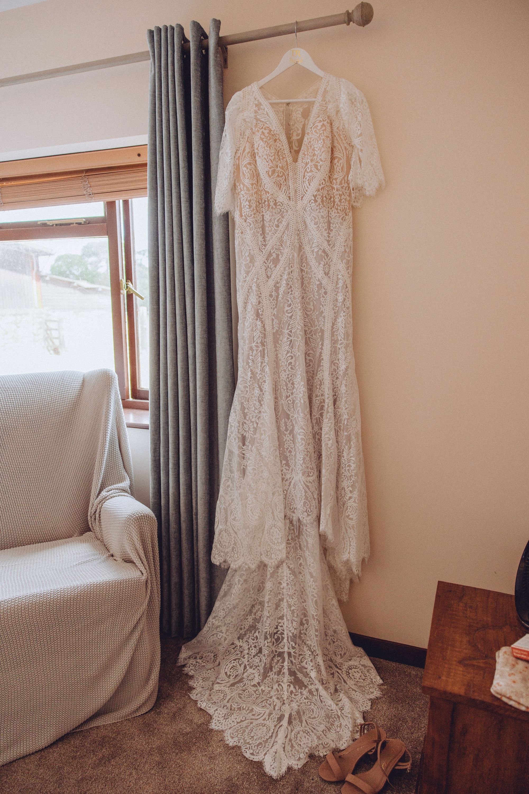 Gorgeous lace wedding dress with half sleeves hanging from the curtain rail. Photo thanks to Fordtography.