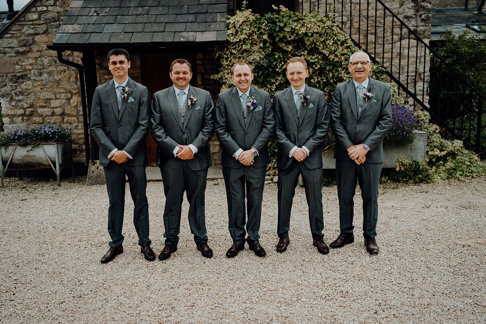 James standing with his groomsmen in the courtyard of Huntsmill Farm in their suits and blue ties. Photo thanks to Sam and Steve Photography.