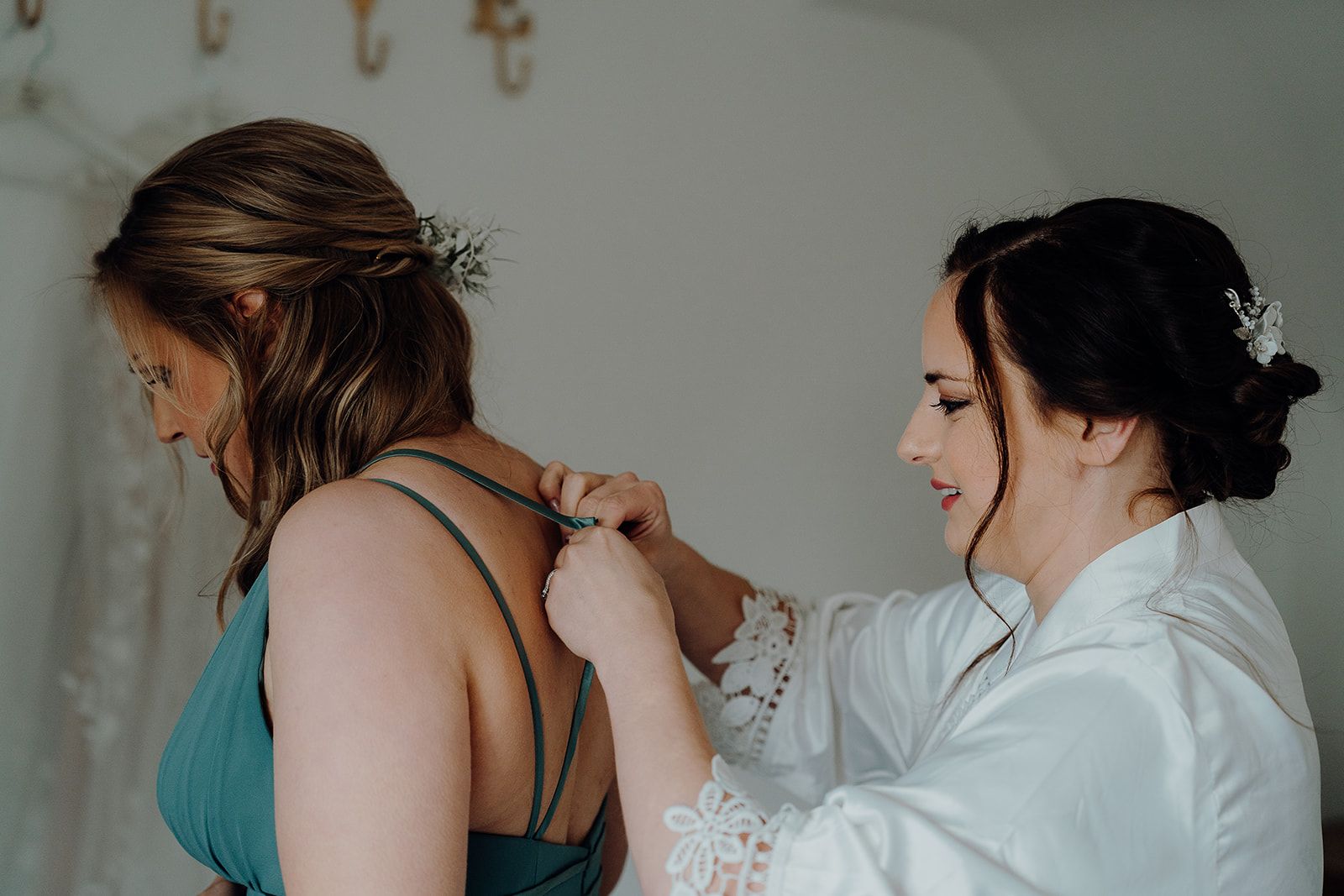 Bride Georgie adjusting the straps of her bridesmaid's dress in the honeymoon suite at Huntsmill Farm before the wedding. Photo thanks to Sam and Steve Photography. 