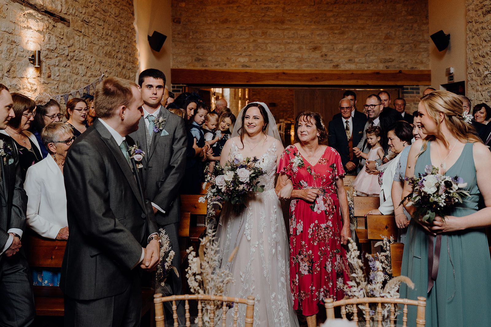 Georgie walking down the aisle with her Mum in the barn at Huntsmill Farm. Photo thanks to Sam and Steve Photography.