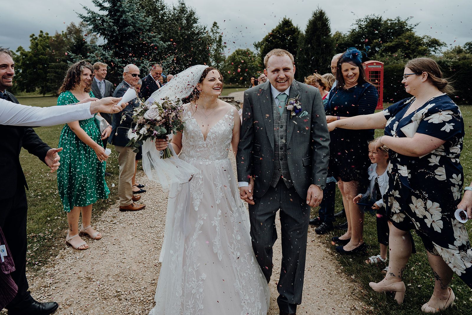 Georgie and James laughing whilst their guests throw confetti. Photo thanks to Sam and Steve Photography.