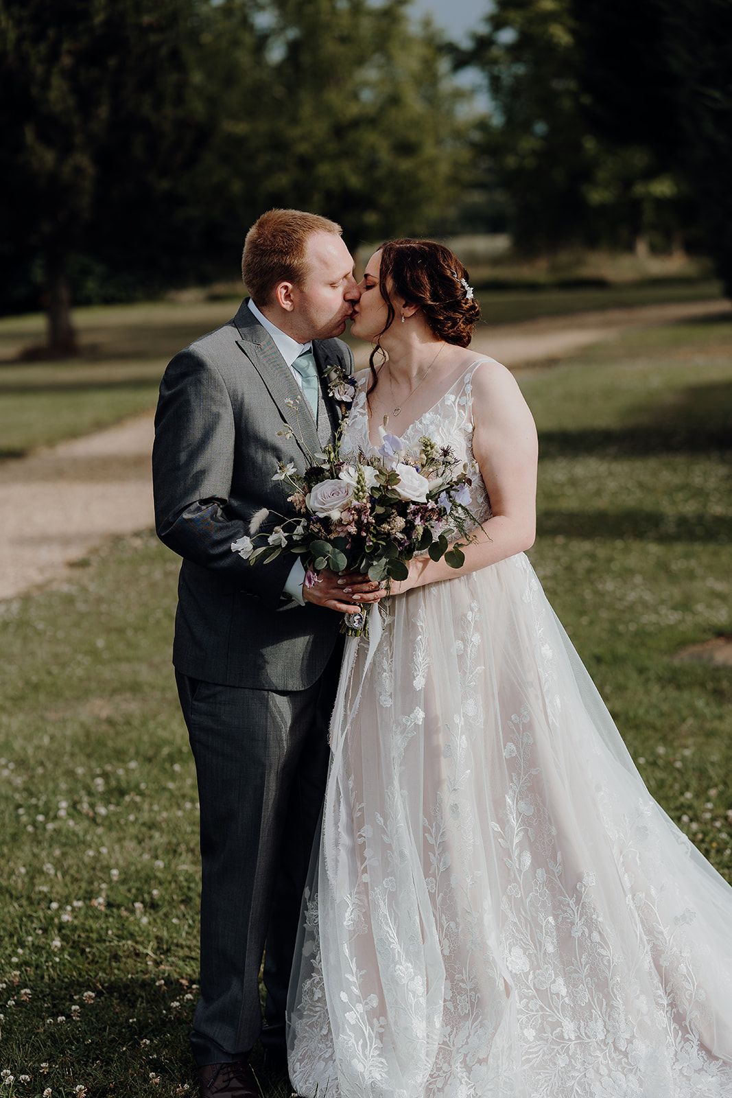 Georgie and James kissing in the gardens of Huntsmill Farm. Photo thanks to Sam and Steve Photography. Fun wedding highlights film by Veiled Productions.