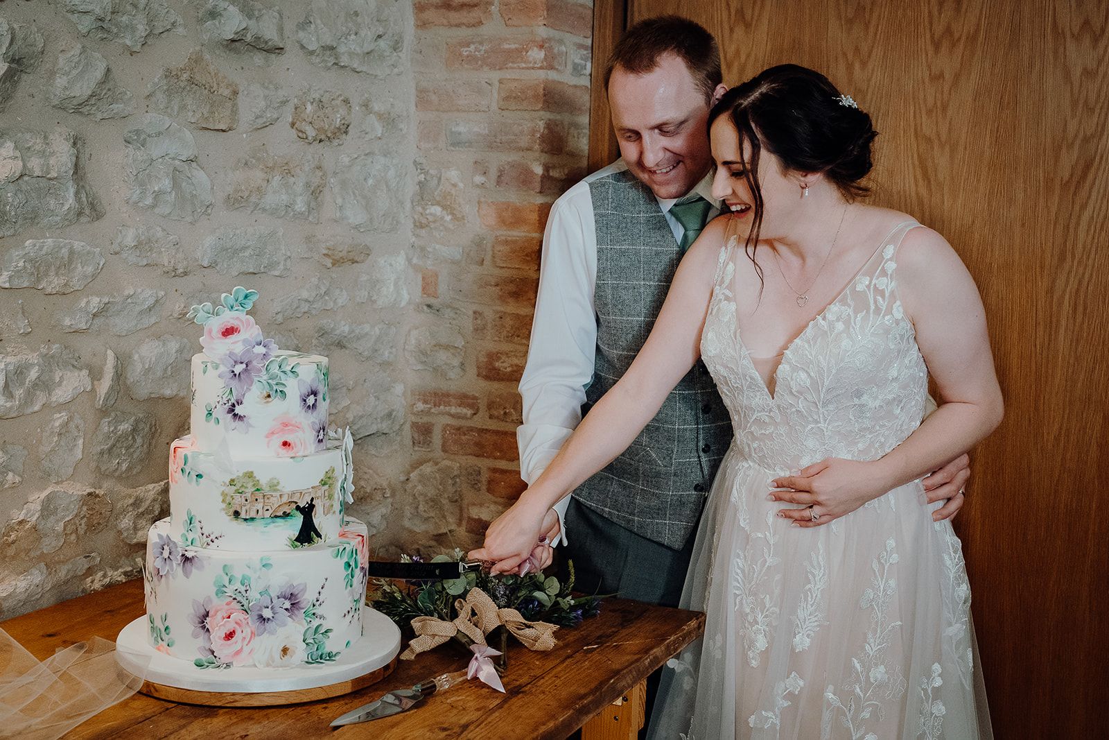 Georgie and James cutting their incredible hand painted wedding cake by Nevie Pie cakes on their wedding day. Photo thanks to Sam and Steve Photography. 