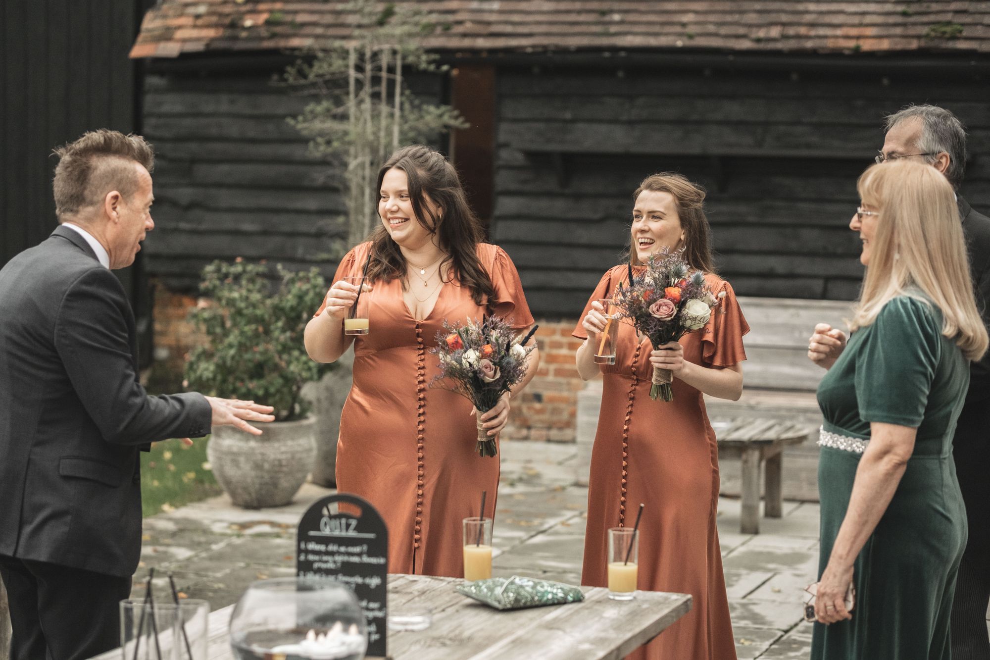 Jennifer's two bridesmaids stood in the courtyard of Lains Barn chatting with guests. Both holding their gorgeous bouquets from Ann Laing and smiling. Photo thanks to The Falkenburgs via Big Day Productions