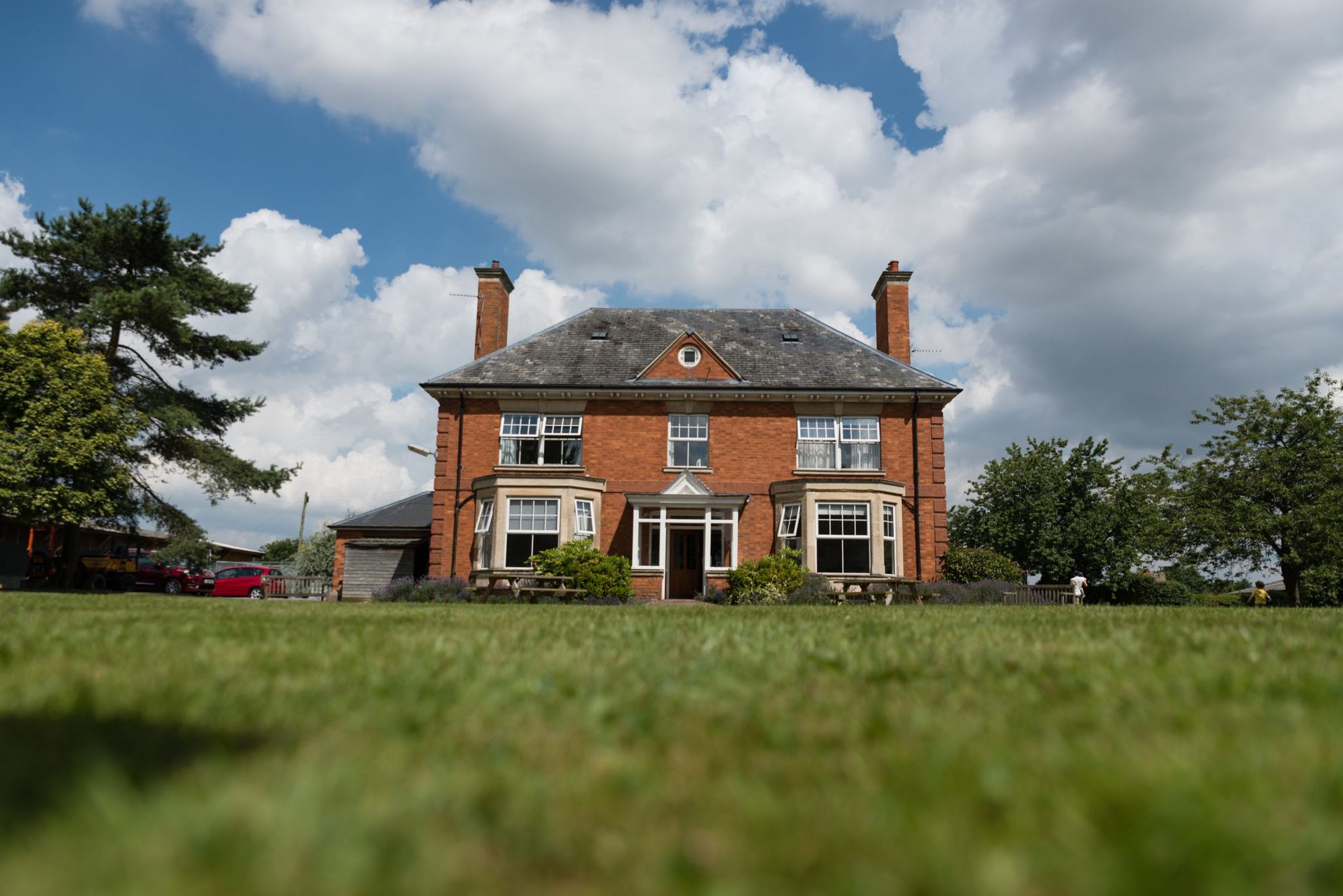 The impressive farmhouse can be viewed in the background which guests can hire the night before and the night of the wedding. The photo is taken low down with the gorgeous lawn out of focus in the foreground. Photo thanks to Tux and Tales Photography.