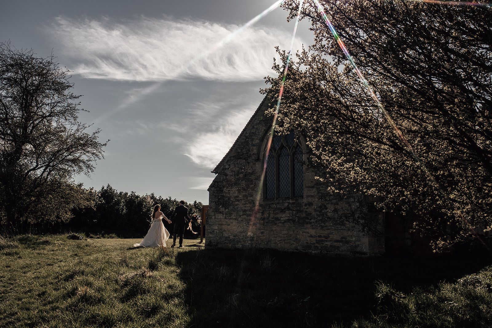 Newlyweds walking hand in hand next to the small chapel onsite at Furtho Manor Farm. Photo thanks to Francesca Checkley Photography.