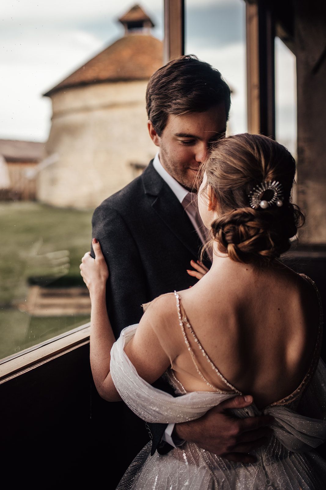 Beautiful photo from inside the barn looking out with the dovecot in the background, the newlyweds stand in the foreground looking at each other. Photo thanks to Francesca Checkley Photography.