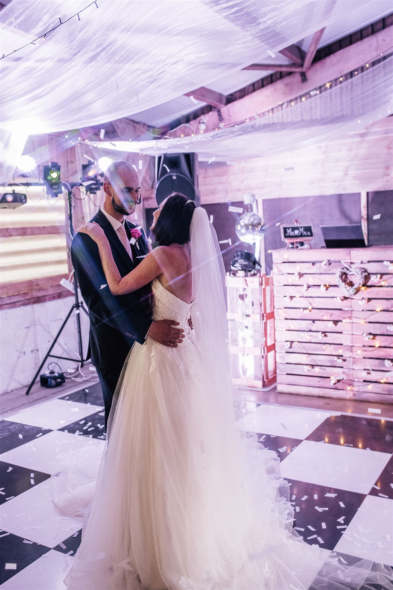 First dance on the dancefloor at Furtho Manor Farm with a rustic wooden DJ booth and a confetti canon has just been released with paper confetti surrounding the couple. Photo thanks to Francesca Checkley Photography.