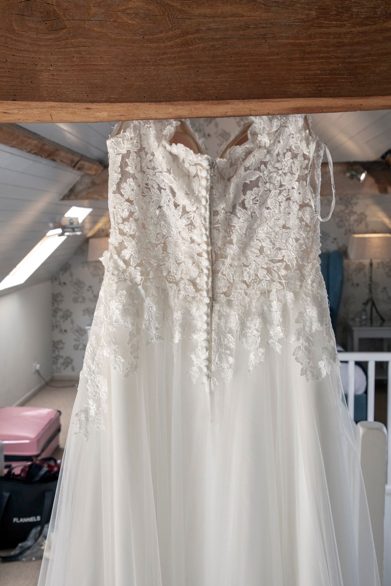 The back of Joanna's wedding dress with buttons and lace detail - hanging up in the Coach House Suite at South Farm. Photo thanks to Nigel Charman Photography.