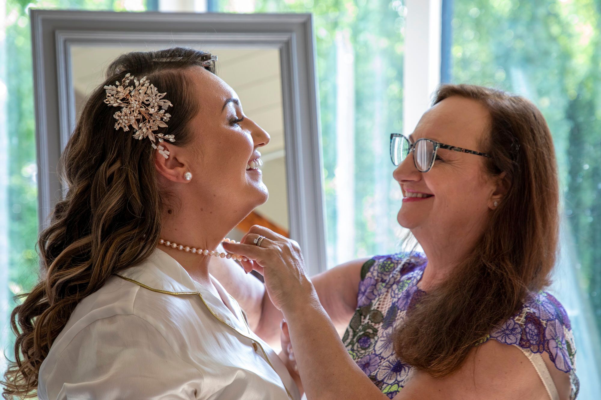Joanna's Mum fastening Joanna's pearl necklace ahead of the wedding ceremony at South Farm in Cambridgeshire. Photo thanks to Nigel Charman Photography. 