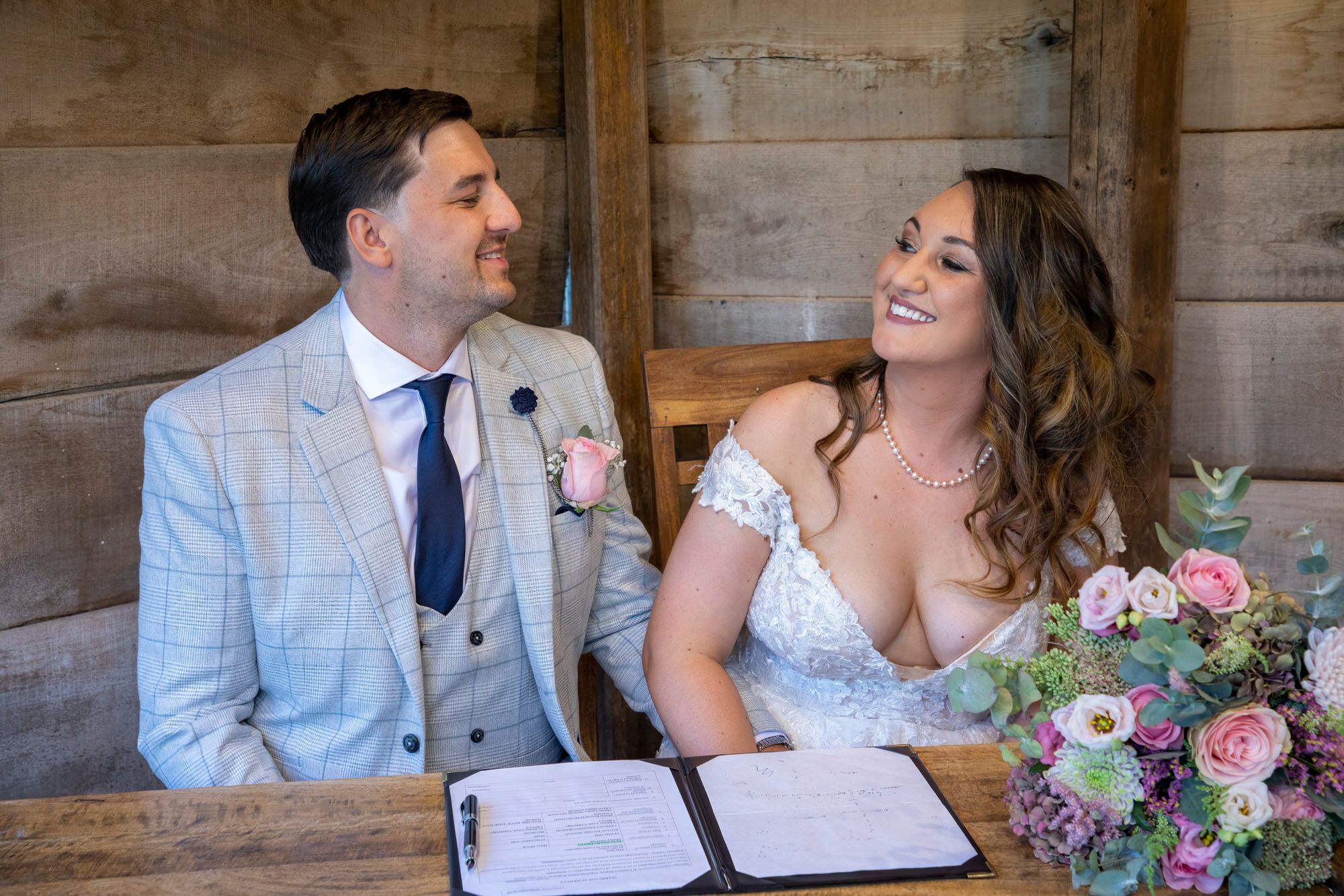 Joanna and Rafal smiling at each other after signing their wedding register in the Summer House at South Farm. Photo thanks to Nigel Charman Photography. 