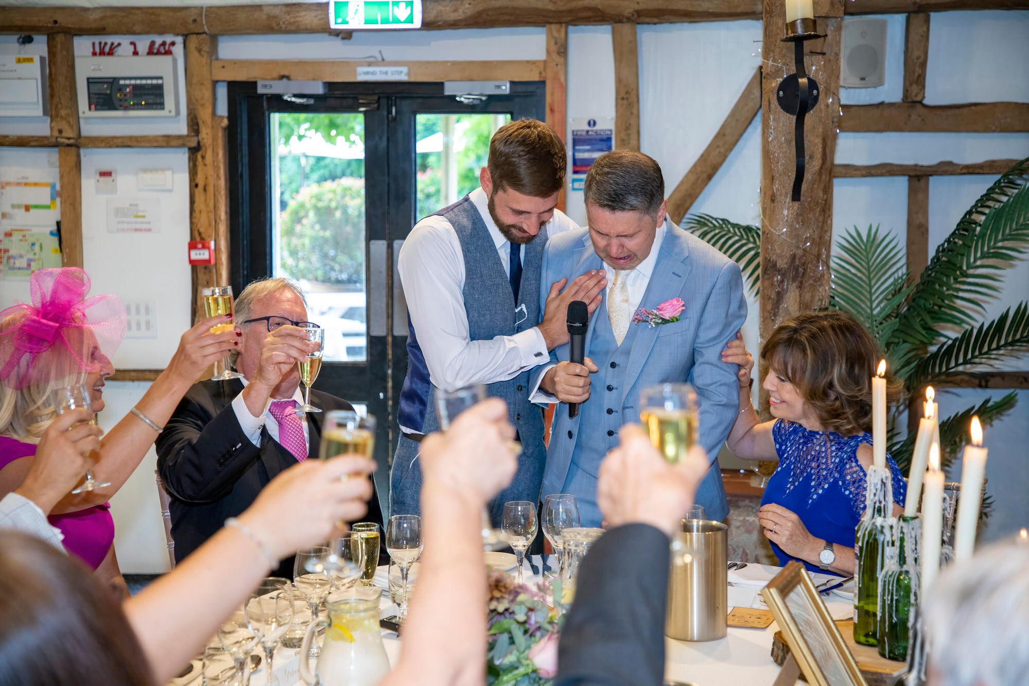 Emotional speeches - Joanna's brother hugging their Dad during his toast. Other guests raising their glasses. Photo thanks to Nigel Charman Photography.