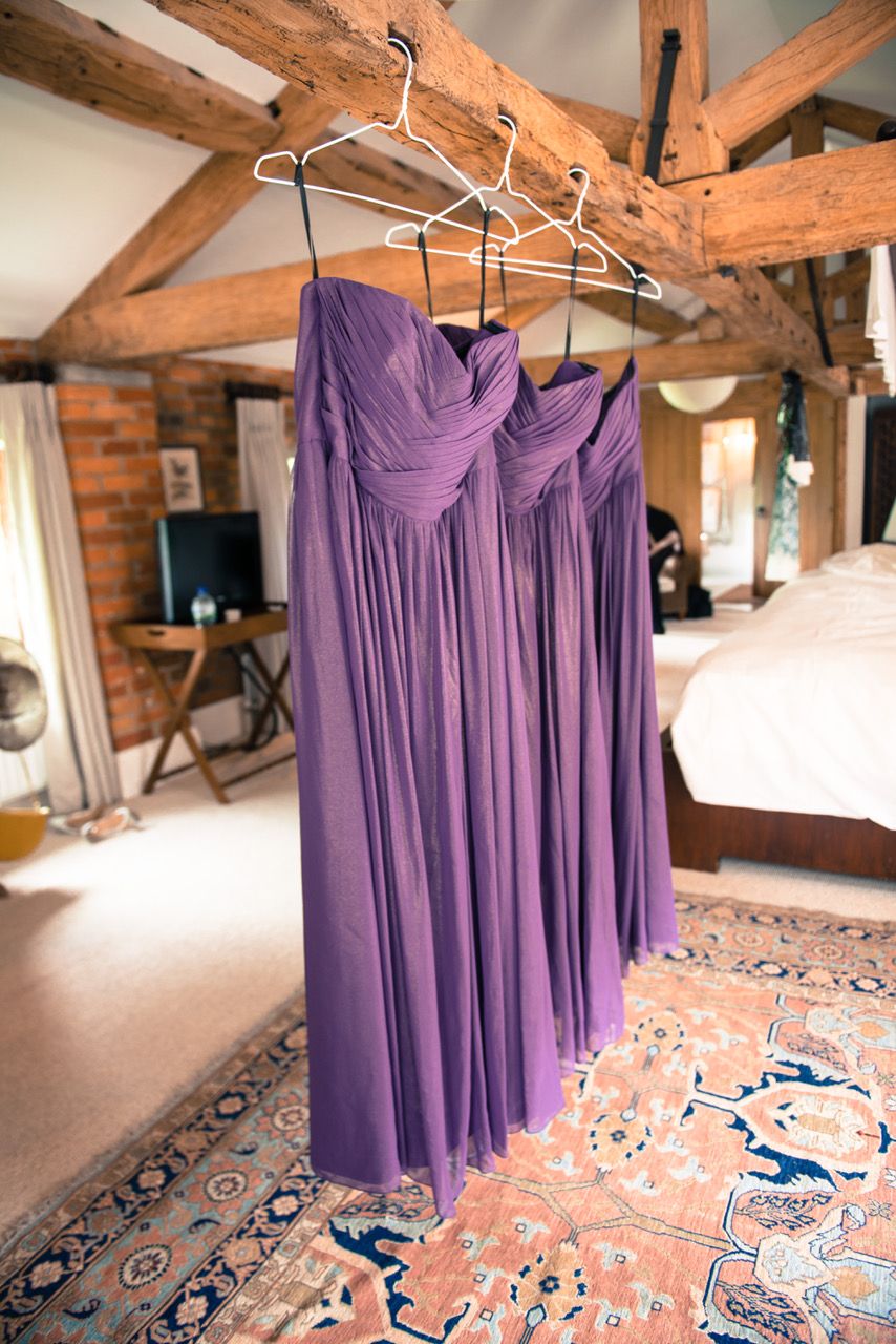 Three purple bridesmaids dresses hanging from the beams in the gorgeous honeymoon suite at Wasing Park. Photo thanks to Zoe Warboys Photography.
