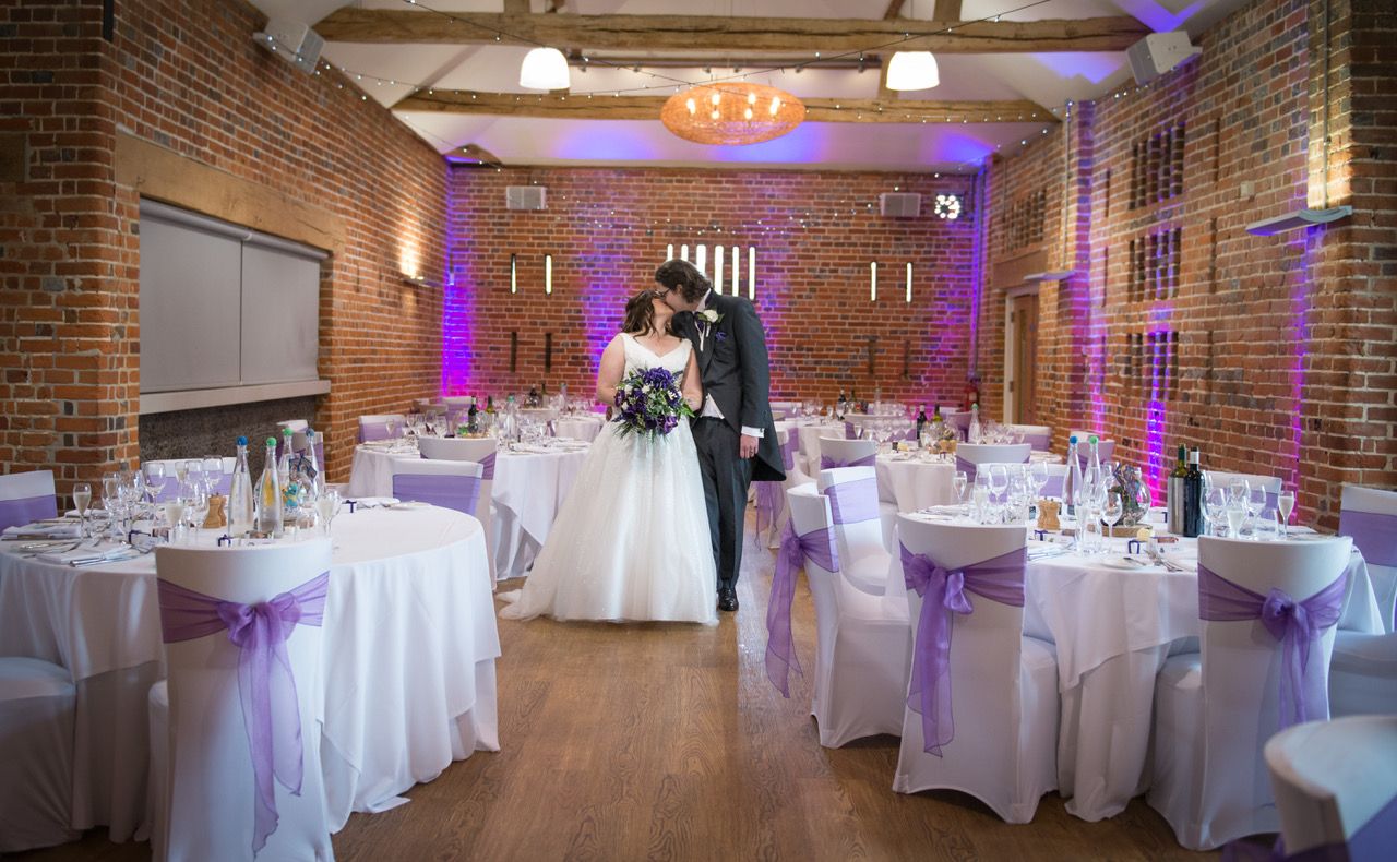 Kelly and Finn steal a kiss stood in the centre of Castle Barn at Wasing Park where they had their wedding breakfast. Photo thanks to Zoe Warboys Photography.