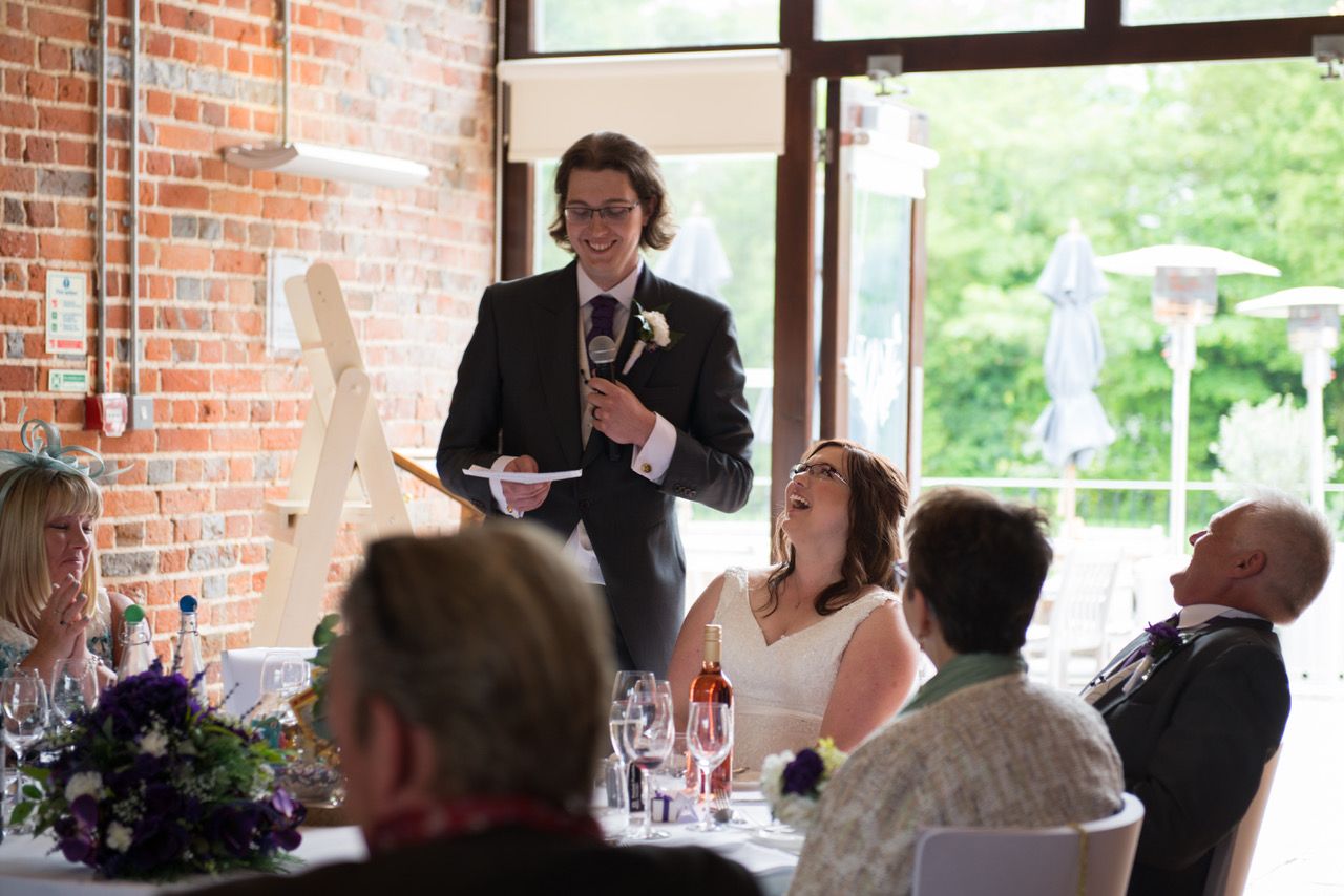 Finn making his speech in the Castle Barn whilst Kelly and the top table guests laugh at what has been said. Photo thanks to Zoe Warboys Photography at Wasing Park.