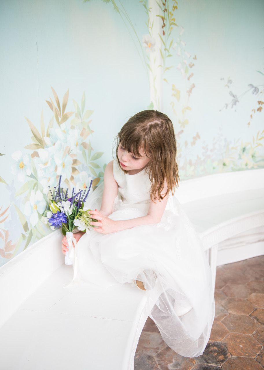 Kelly and Finn's daughter sitting in the Summerhouse at Wasing Park looking down at her flowers. Photo thanks to Zoe Warboys Photography.