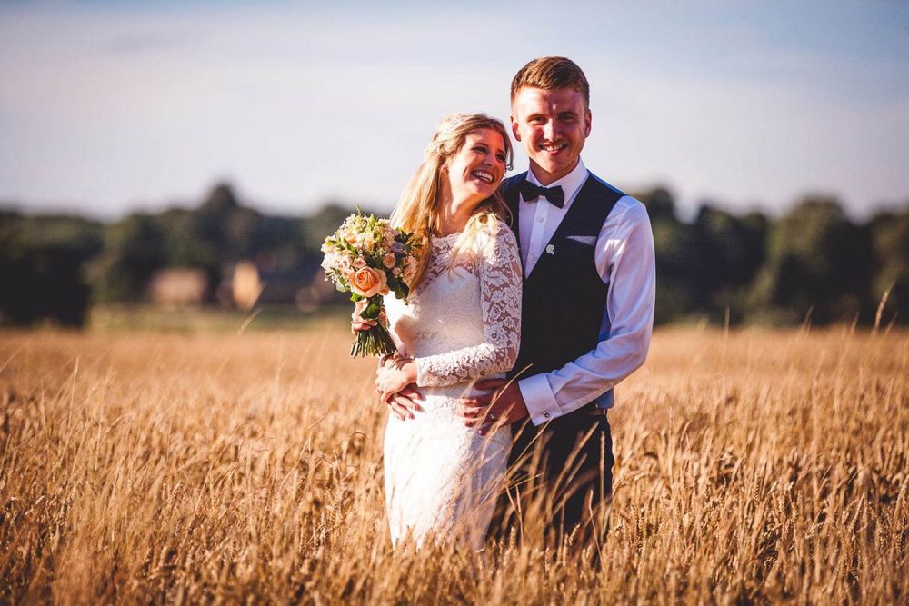 Couple standing in wheat fields at their Oxfordshire Wedding.